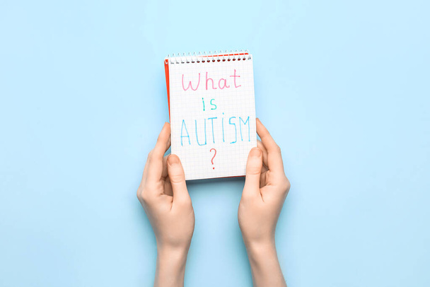 Woman and notebook with text WHAT IS AUTISM? on blue background - Foto, Imagen