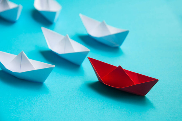 Leadership Concept - Rotes Papierschiff-Origami, das den Rest des weißen Papierschiffs auf blauem Umschlaghintergrund anführt. Kopierraum - Foto, Bild