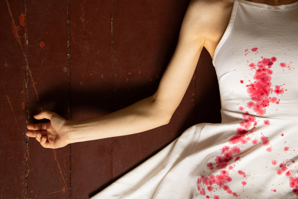 На полу дома лежит убитая и истязаемая украинка в белом платье и пятнах крови, акция протеста украинских женщин, защищающих женщин от российских солдат - Фото, изображение