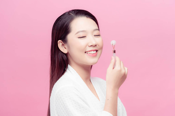 Woman caring of her beauty face with cosmetic tool. Skin care concept. Girl holds item for makeup. - Fotó, kép