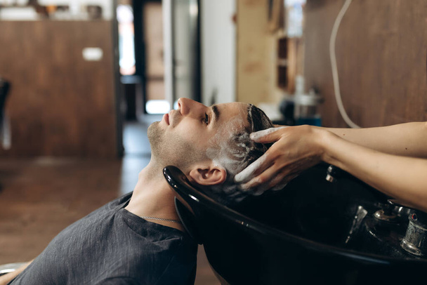 Hairdresser man washes client's head in barbershop - Fotoğraf, Görsel