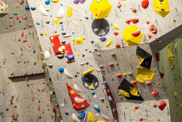 Artificial rock climbing wall with various colored grips - Fotó, kép