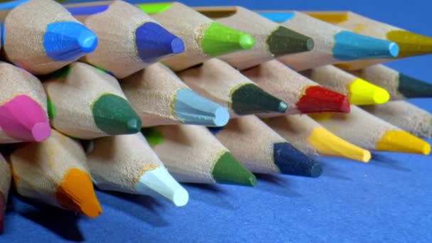 Barevné tužky jezdec výstřel. Toto stock video obsahuje sbírku různých barevných tužek umístěných na modrém stole. - Záběry, video