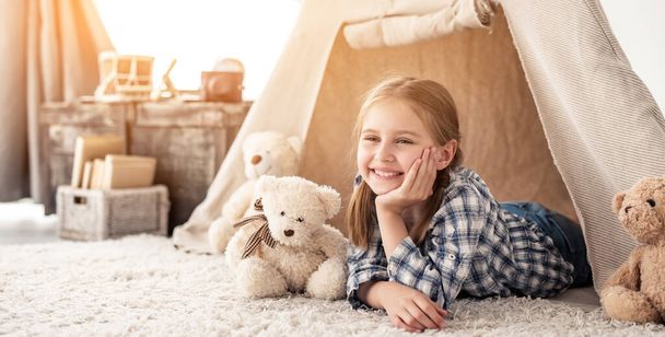 klein meisje liggend in wigwam met teddies - Foto, afbeelding