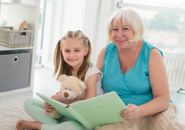Granny reading book to little granddaughter - Foto, immagini