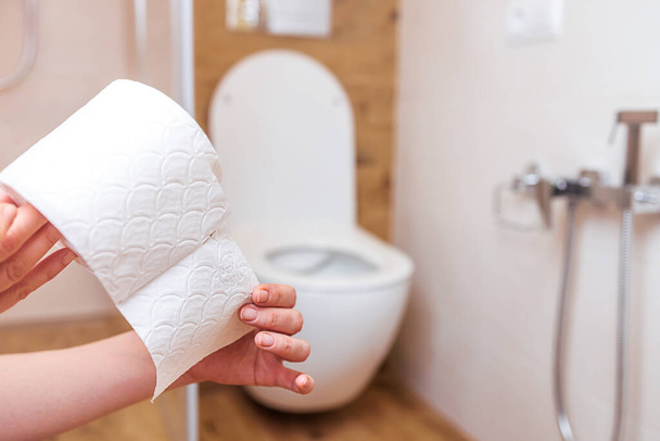 primer plano en las manos de una mujer papel higiénico en el fondo del baño - Foto, Imagen