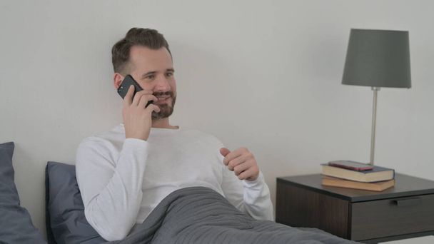 Férfi beszél Call on Smartphone az ágyban - Fotó, kép