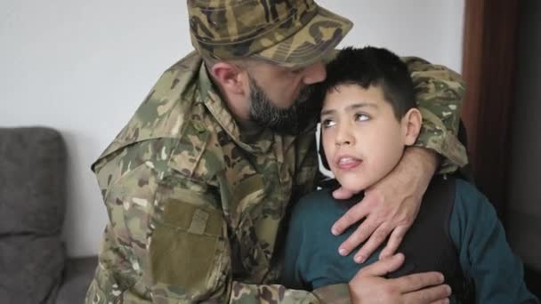 Vojenský voják líbá svého syna se zdravotním postižením doma - Záběry, video
