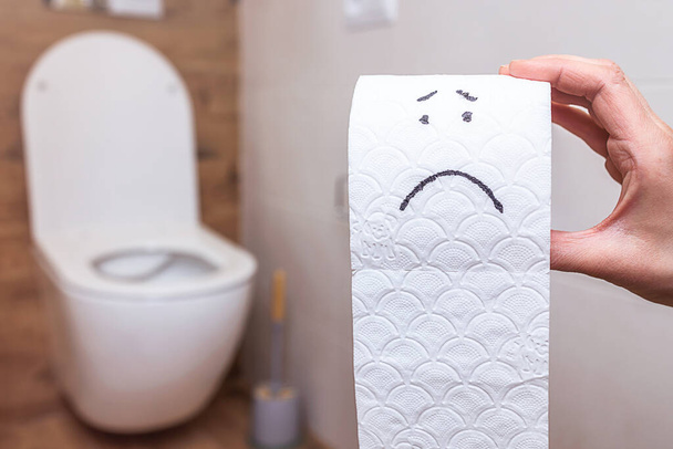 Смішне обличчя намальоване на рулоні туалетного паперу на фоні ванної кімнати
 - Фото, зображення