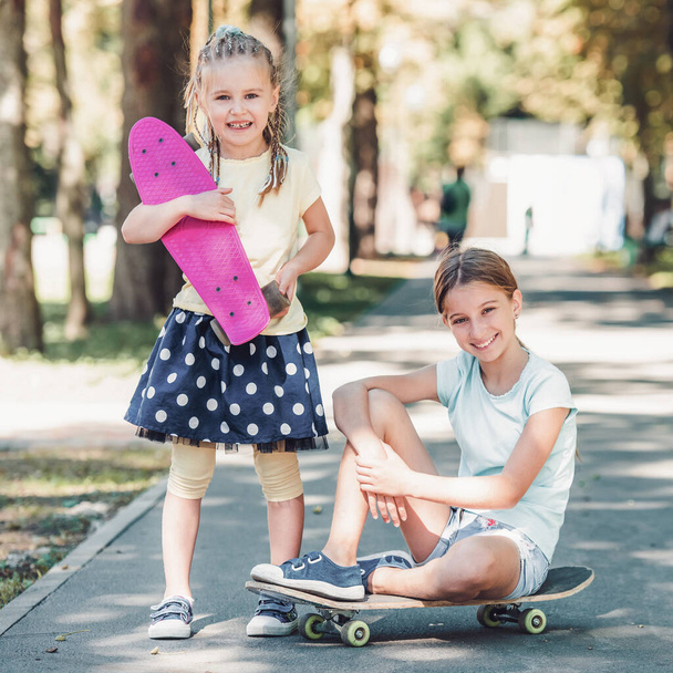 Girls with skateboards in the park - Фото, изображение