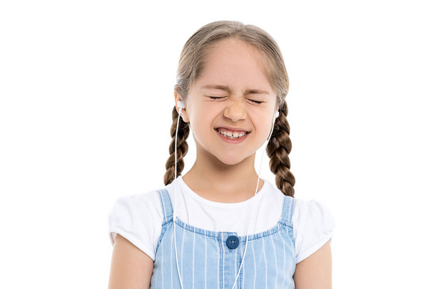menina animado em fones de ouvido com fio de pé com olhos fechados isolados em branco - Foto, Imagem