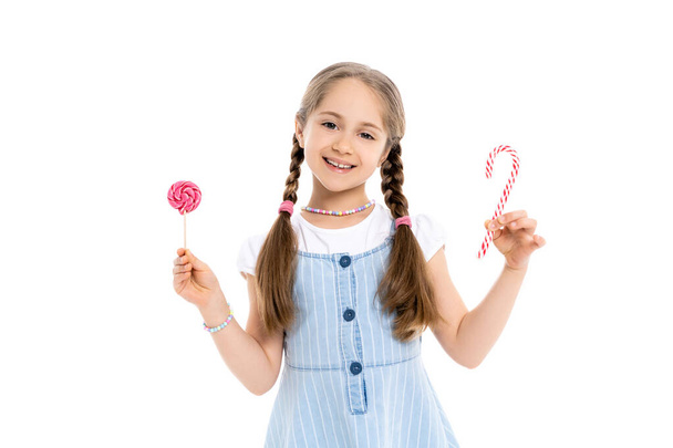 excited girl with candy cane and lollipop looking at camera isolated on white - Photo, Image