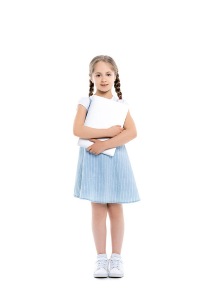 full length view of girl in blue dress standing with laptop on white - Foto, afbeelding