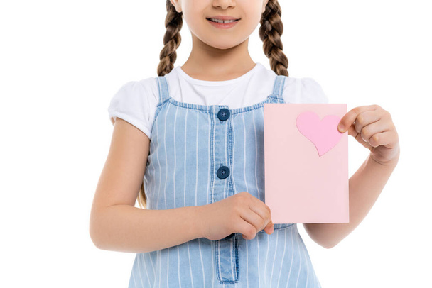 обрезанный вид улыбающейся девушки в синем платье ремешок держа карту с розовым сердцем изолированы на белом - Фото, изображение