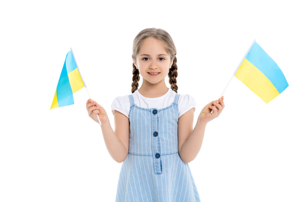 Küçük Ukrayna bayraklarıyla mutlu bir kız kameraya gülümsüyor. - Fotoğraf, Görsel