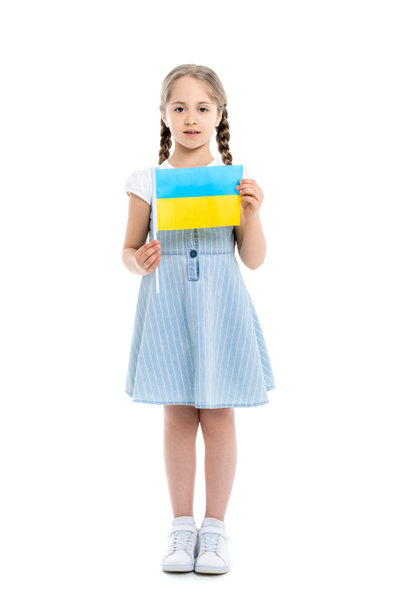 vista completa de la muchacha en vestido azul sosteniendo pequeña bandera ucraniana en blanco - Foto, Imagen