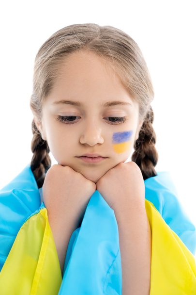 frustrata ragazza coperta di bandiera ucraina che si tiene per mano vicino al viso isolato su bianco - Foto, immagini