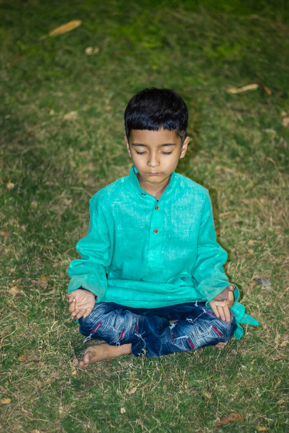 nuori lapsi meditoi perinteisessä mekossa illalla eri näkökulmista - Valokuva, kuva