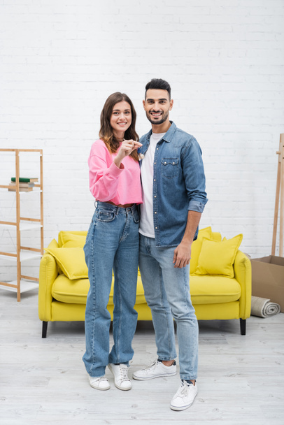 Positive multiethnic couple holding key and looking at camera at home  - Zdjęcie, obraz