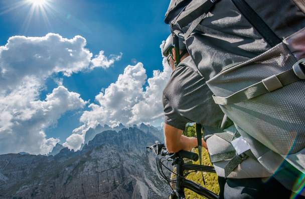 Letni rower górski z plecakiem. Mężczyźni rasy kaukaskiej na szlaku górskim Gdzieś we włoskich Dolomitach. - Zdjęcie, obraz