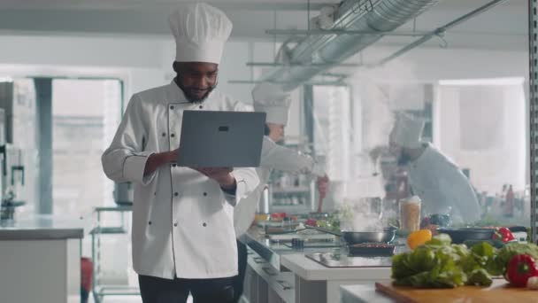 Afrykański amerykański kucharz gotowanie przepis kulinarny z laptopem - Materiał filmowy, wideo