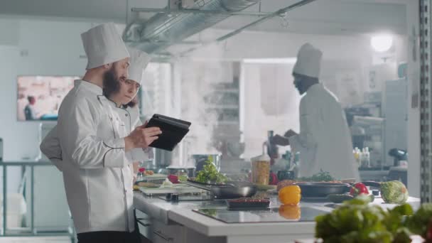 Equipo de cocineros usando tableta digital para preparar auténtica comida gourmet - Metraje, vídeo
