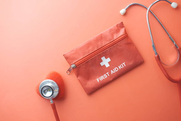 top view of first aid kit, heart shape symbol and stethoscope on red  - Foto, Imagen
