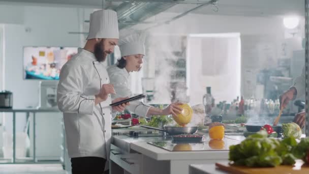 Cuoco maschio che analizza la ricetta culinaria su tablet digitale in cucina - Filmati, video