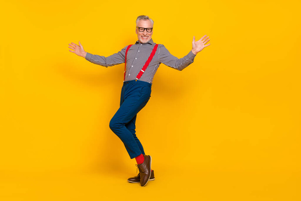 Full length photo of cheerful good mood grandpa dancing in nightclub wear suspenders isolated on yellow color background - Foto, Imagem