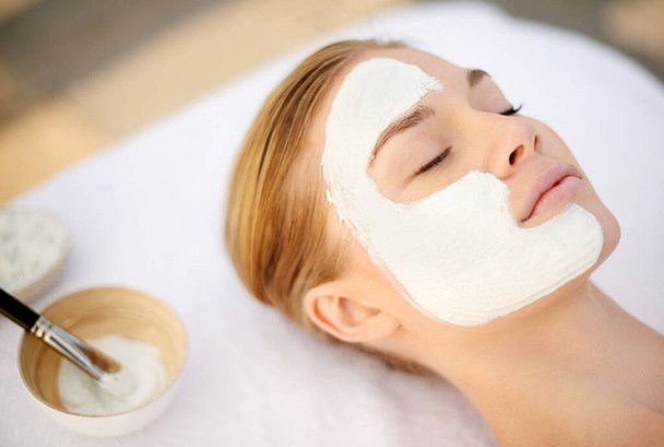 Indulging in a deep cleansing masque. Shot of a young woman getting a facial at a spa. - Foto, Imagen