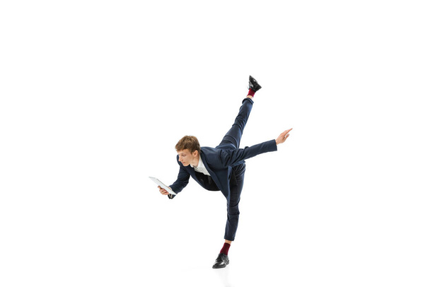 Man in office style clothes dancing and using tablet isolated on white studio background. Business, start-up, open-space, inspiration concept. - Φωτογραφία, εικόνα
