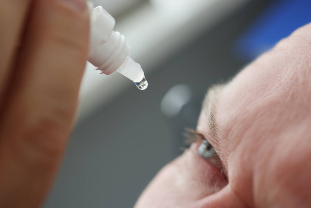 Adult man carefully looks at drops of vision, closeup - Фото, зображення