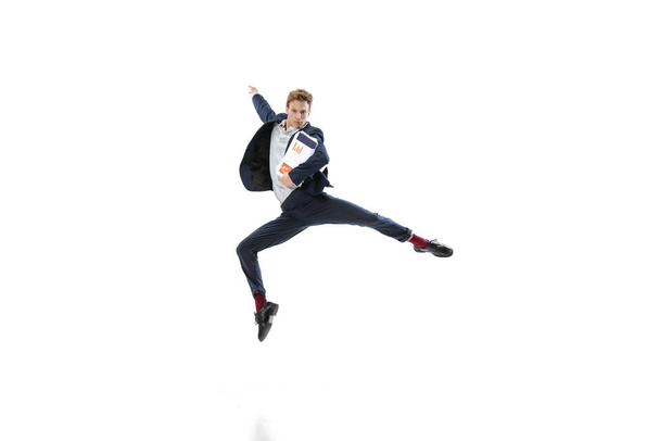 Νεαρός με σκούρο κοστούμι πηδάει, πετάει απομονωμένος σε λευκό φόντο. Τέχνη, κίνηση, δράση, ευελιξία, έμπνευση. - Φωτογραφία, εικόνα