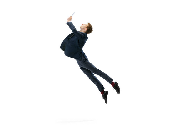 Young man in office style clothes jumping isolated on white studio background. Business, start-up, open-space, inspiration concept. - 写真・画像