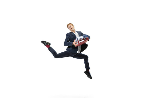 Young man in dark business suit jumping, flying isolated on white background. Art, motion, action, flexibility, inspiration concept. - Fotoğraf, Görsel