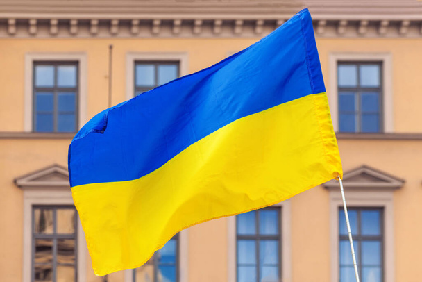 Ukraińska flaga wieje na tle architektury. Wsparcie dla Ukrainy. - Zdjęcie, obraz