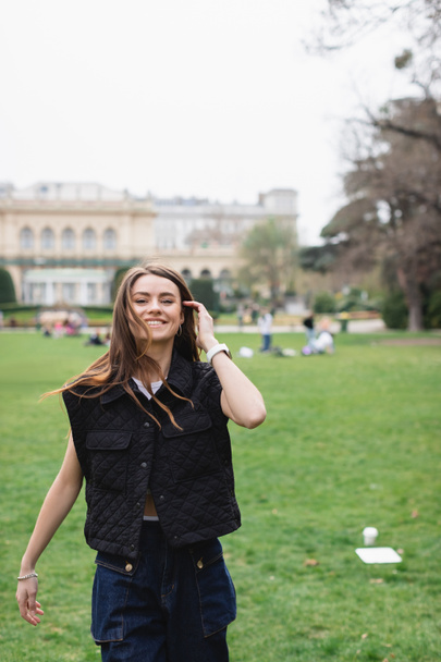 young cheerful woman in sleeveless jacket in green park  - 写真・画像