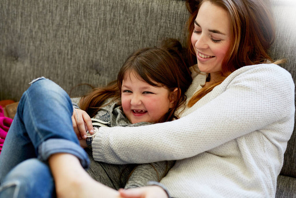 Acurrucarse en el sofá con mamá. Foto de una madre jugando con su hija pequeña en el sofá en casa. - Foto, Imagen