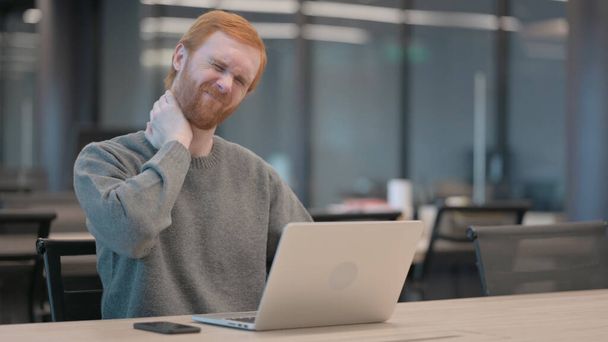 Ofiste dizüstü bilgisayar kullanırken boyun ağrısı çeken genç adam.  - Fotoğraf, Görsel