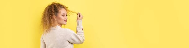 Young cheerful girl smiling at the camera while standing on a yellow background close-up. - Photo, image