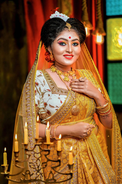 Portrait of a beautiful bengali bride in yellow saree and gold jewelry.  - Photo, Image