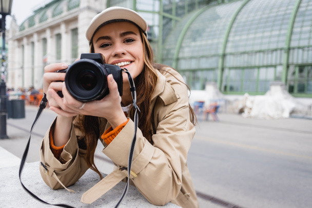 счастливого фотографа в пензлике и бейсбольной кепке, делающих фото на цифровой камере  - Фото, зображення