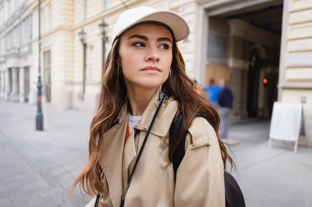 pretty woman in trench coat and baseball cap  - 写真・画像
