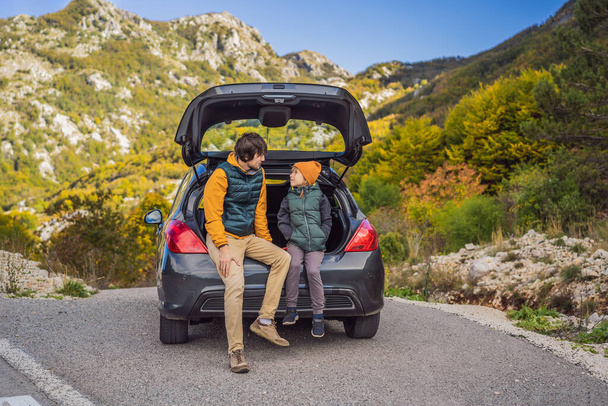 Dad and son are resting on the side of the road on a road trip. Road trip with children concept - Φωτογραφία, εικόνα