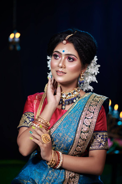 Portrait of a beautiful girl in bengali reception makeover. Wearing blue benarasi sare. Gold jewelry.  - Foto, Bild