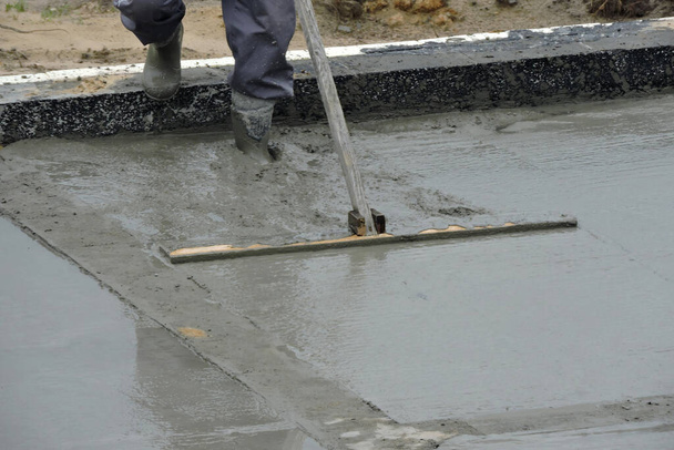 Egy építőmunkás lebegteti a nedves betont. - Fotó, kép