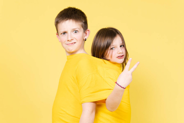 Dva přátelé nebo bratři ve stejné velké košili izolované na žlutém pozadí. Koncept přátelství v dětství - Fotografie, Obrázek
