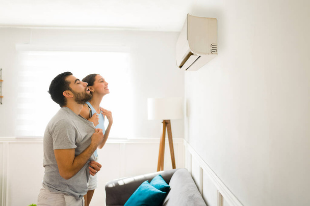 Side view of a relaxed happy woman and man cooling with the cold air flow of the air conditioning  - Fotoğraf, Görsel