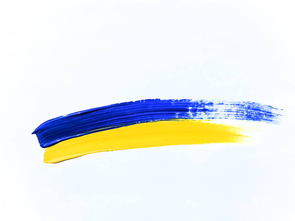 The stripes of the flag of Ukraine are painted with paints on a white background. The flag of Ukraine on a white background. Bright colors. Yellow-blue flag. No to war. A flag is painted with a brush. - 写真・画像