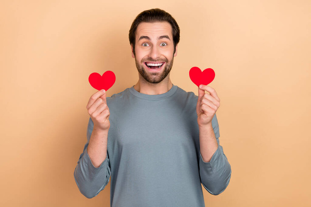 Photo of young excited man hold hands small heart shape romantic cardiac isolated over beige color background - Fotografie, Obrázek